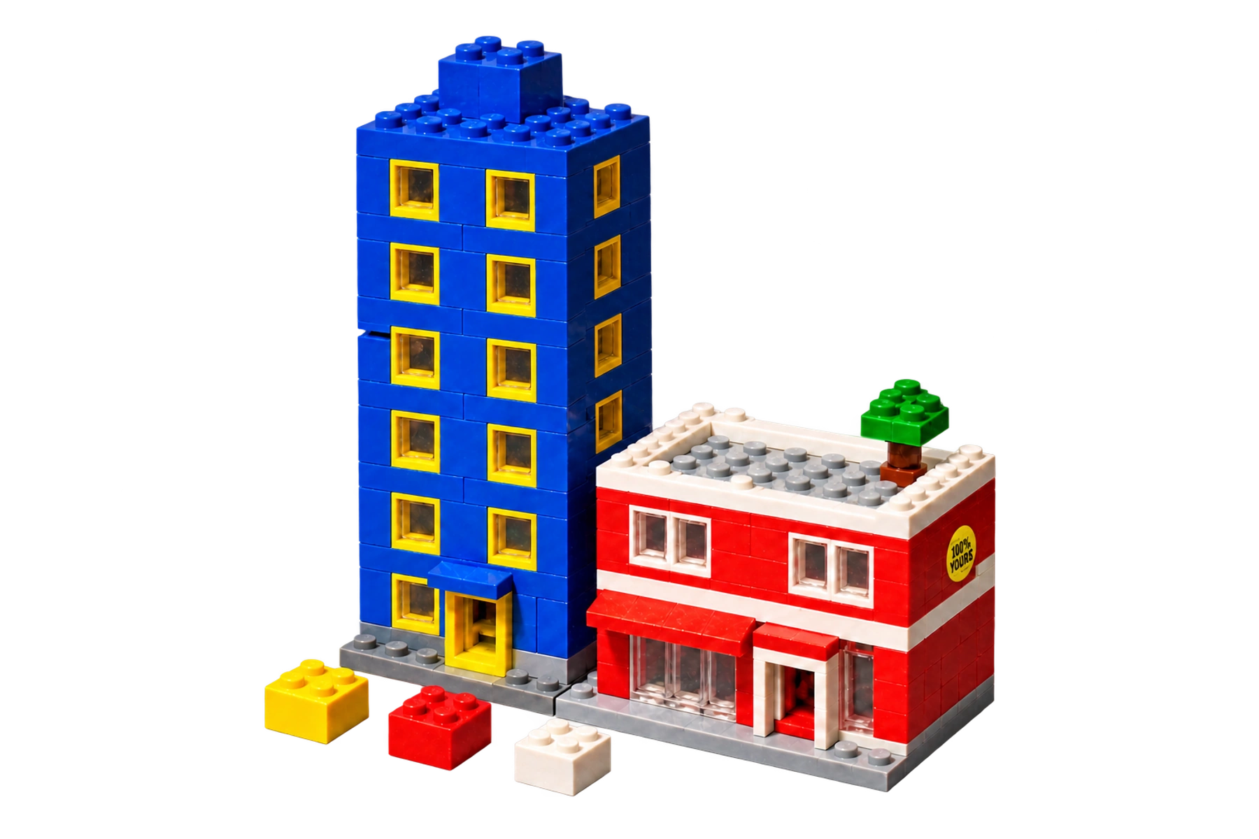 Two toy-brick buildings, a blue tower and a red shop, with a yellow 100% yours sticker.
